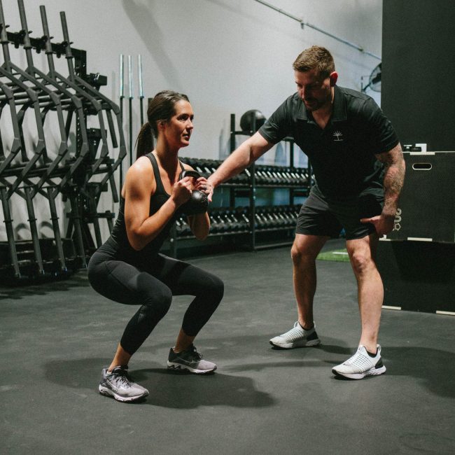 Matt Gulliver, the head trainer of Oak and Iron works privately with a client on her squat form during a personal training session