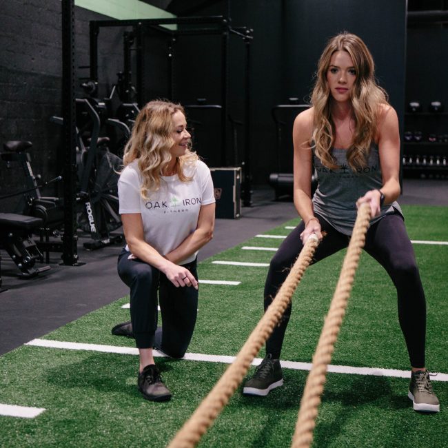 Personal Trainer, Kayla Scott helps guide a new gym go-er through an intense battle rope exercise.