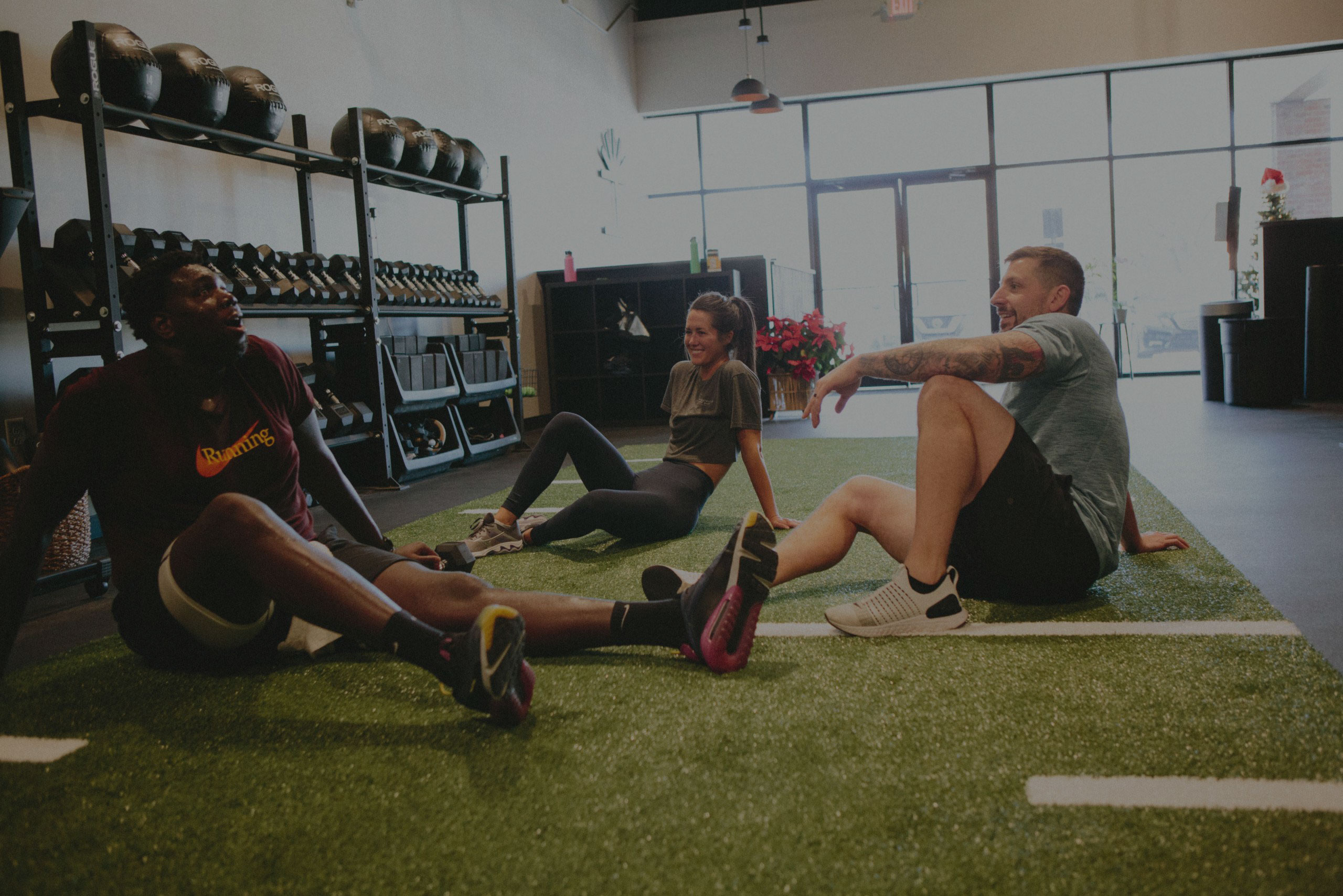 Trainers and Gym Go-ers sit on the artificial turf to catch their breath after a drive class.