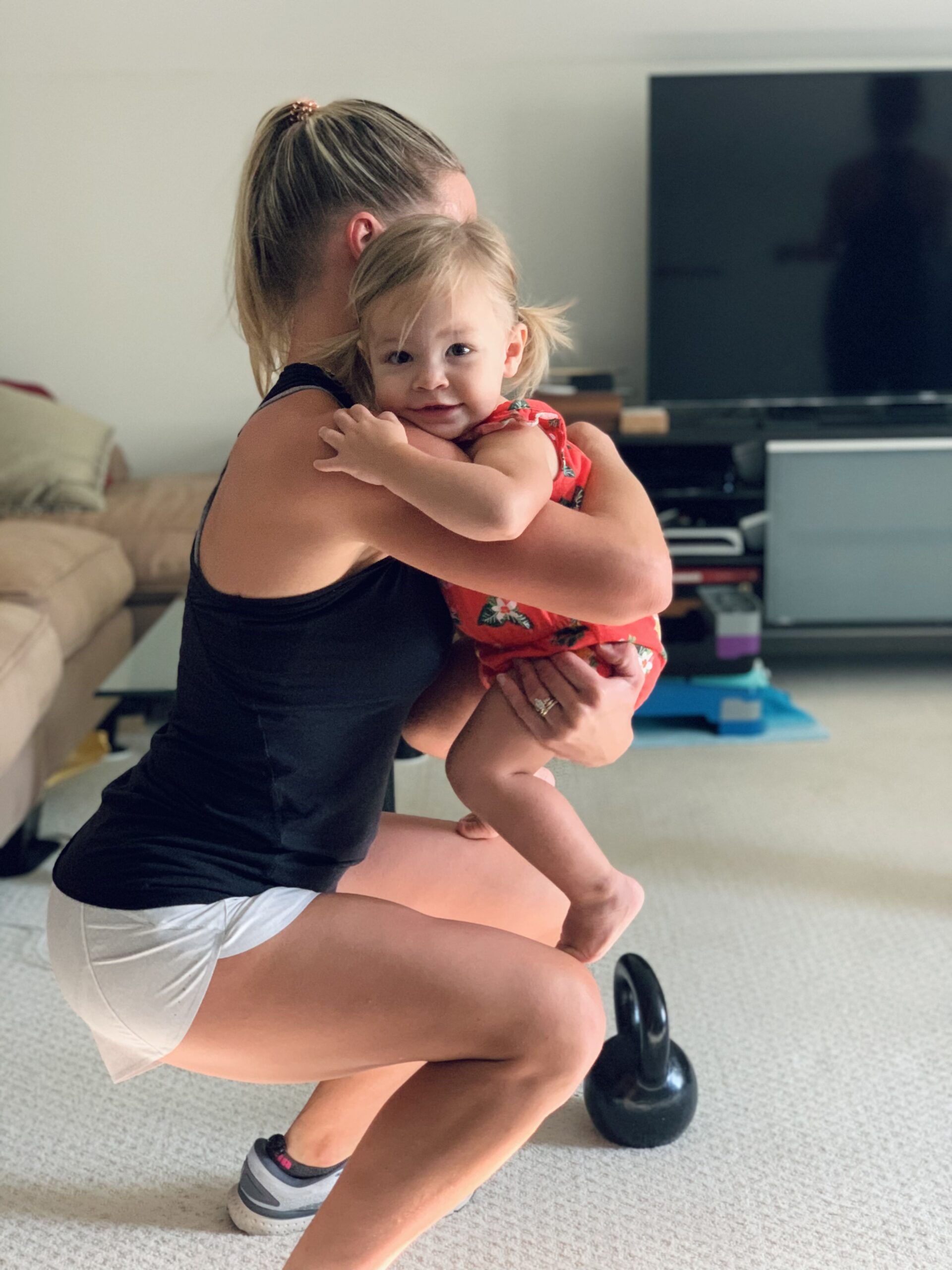 Mom performing squat while holding their child.