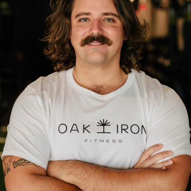 Fitness Coach Andrew Barsuhn posing for a headshot in the gym's group fitness area.