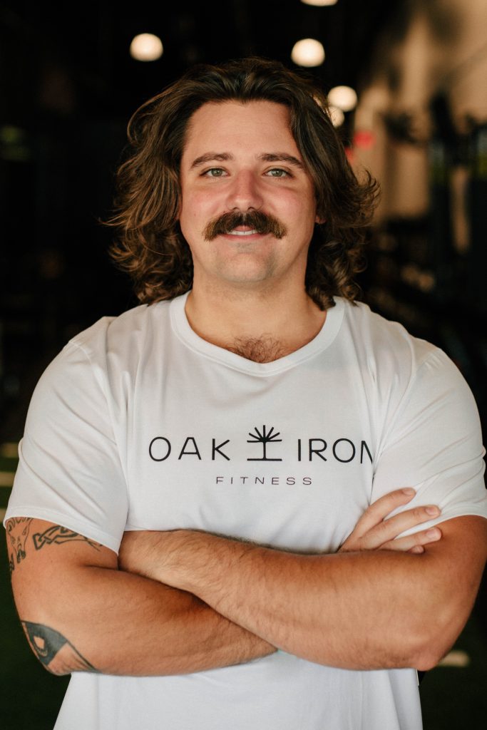 Fitness Coach Andrew Barsuhn posing for a headshot in the gym's group fitness area.