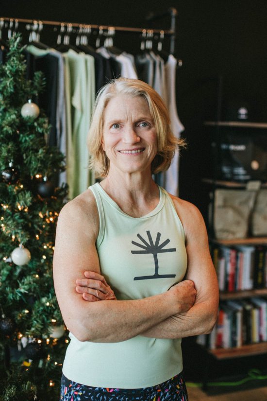 Mary Lloyd, Member of the Month, smiling in front of the gym's Christmas Tree.