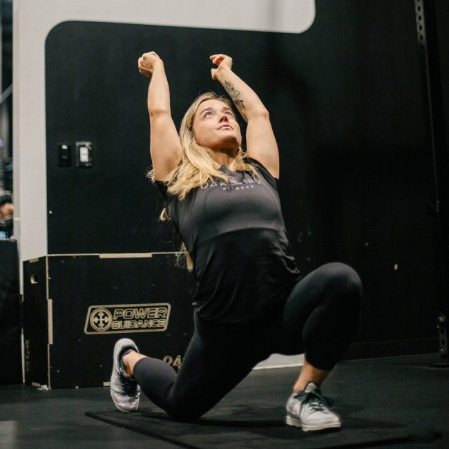 Rachel Nicholson performing mobility work with arms stretched overhead in a low lunge