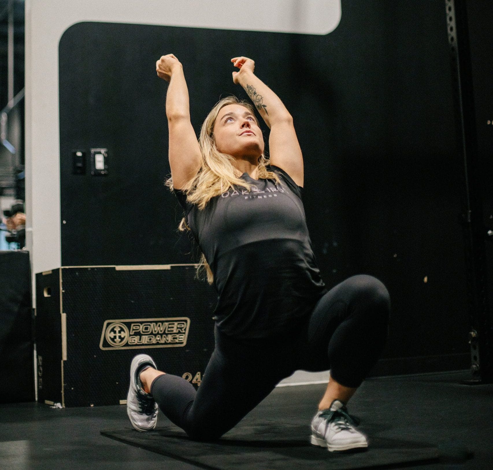 Rachel Nicholson performing mobility work with arms stretched overhead in a low lunge
