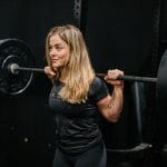 Rachel Nicholson, CSCS certified strength coach and personal trainer with a barbell racked across shoulders. Why Women Should Lift Heavy Weights