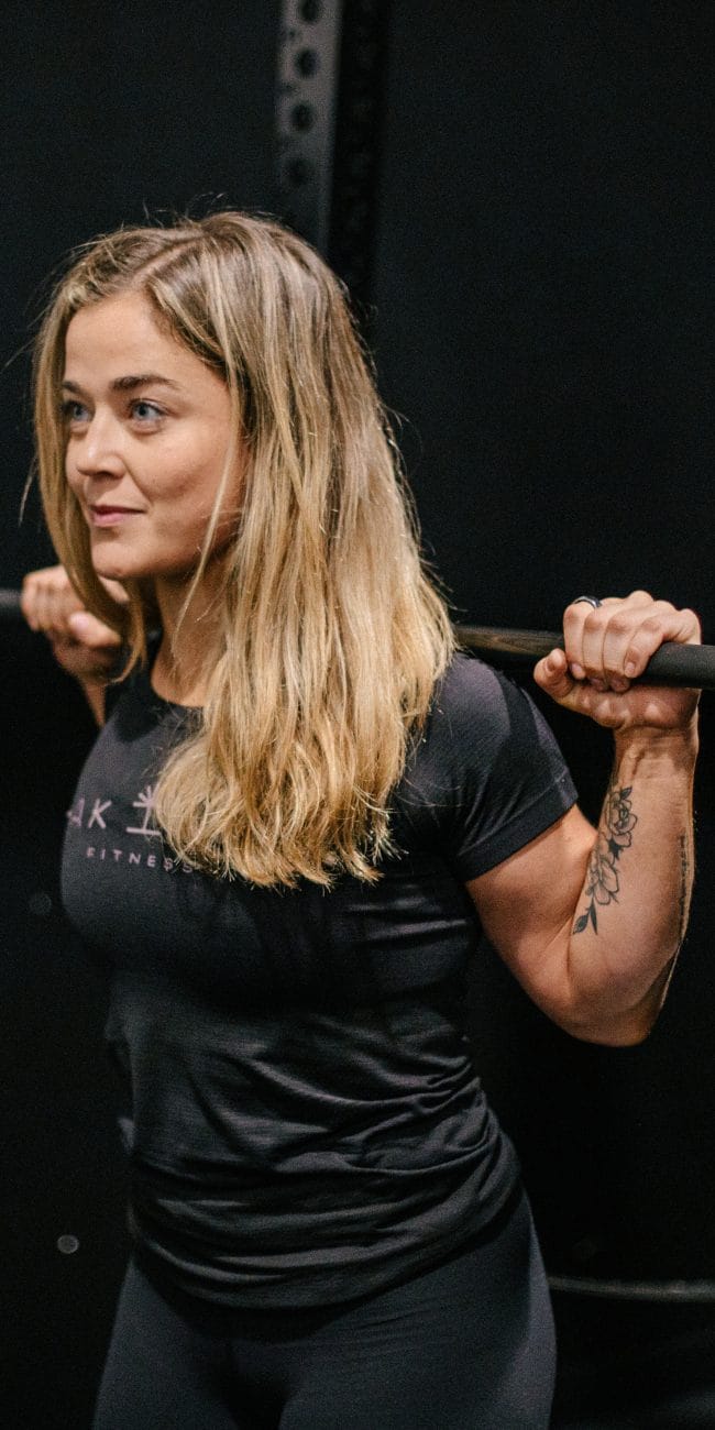 Rachel Nicholson, CSCS certified strength coach and personal trainer with a barbell racked across shoulders. Why Women Should Lift Heavy Weights