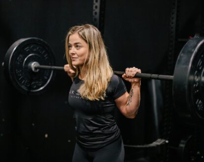 Rachel Nicholson, CSCS certified strength coach and personal trainer with a barbell racked across shoulders. Why Women Should Lift Heavy Weights