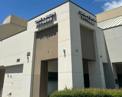 Exterior view of Oak and Iron Fitness gym building in Cary, North Carolina, showing a modern brick-and-glass structure with the gym’s signage visible above the entrance.